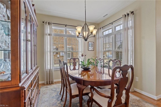 dining space with light wood-style floors, visible vents, baseboards, and a notable chandelier