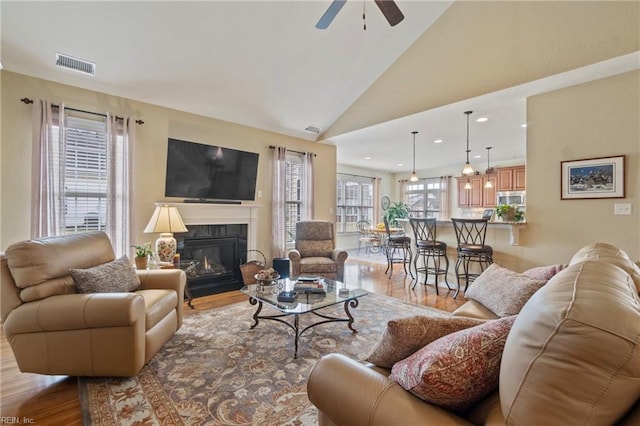 living room with a glass covered fireplace, visible vents, and wood finished floors