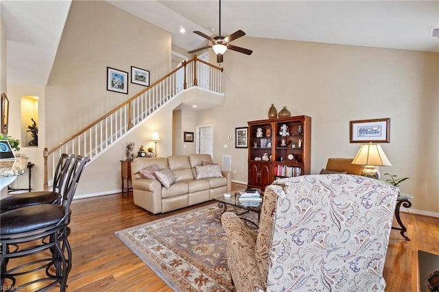 living room featuring a ceiling fan, baseboards, stairway, and wood finished floors