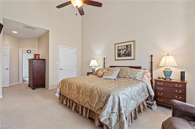 bedroom with light carpet, visible vents, baseboards, ceiling fan, and a high ceiling