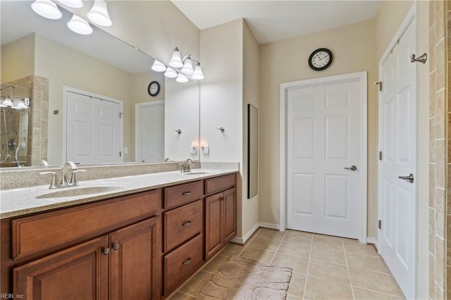 bathroom featuring tile patterned flooring, tiled shower, a sink, and double vanity