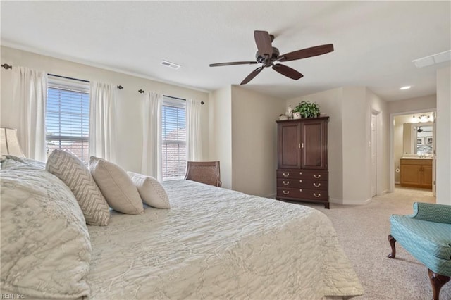 bedroom with ensuite bathroom, light colored carpet, a ceiling fan, baseboards, and visible vents