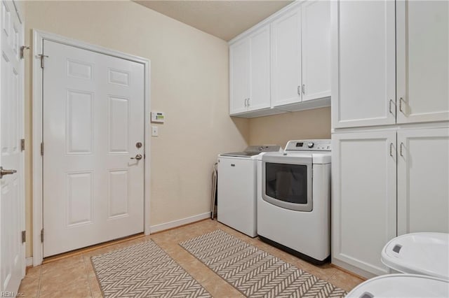 clothes washing area with cabinet space, baseboards, light tile patterned flooring, and washing machine and clothes dryer