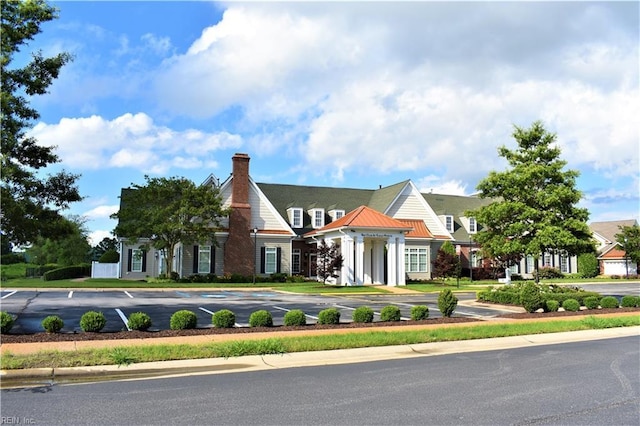 view of front of house with uncovered parking, metal roof, a standing seam roof, and a chimney