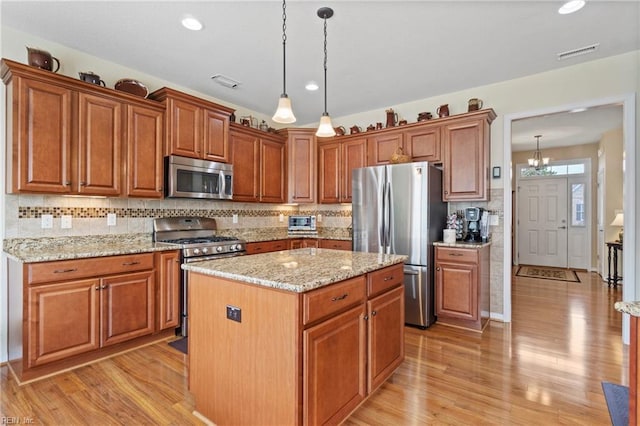 kitchen with light wood-style flooring, a kitchen island, visible vents, and stainless steel appliances