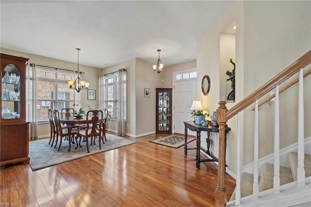 entryway featuring baseboards, light wood finished floors, stairway, and a notable chandelier