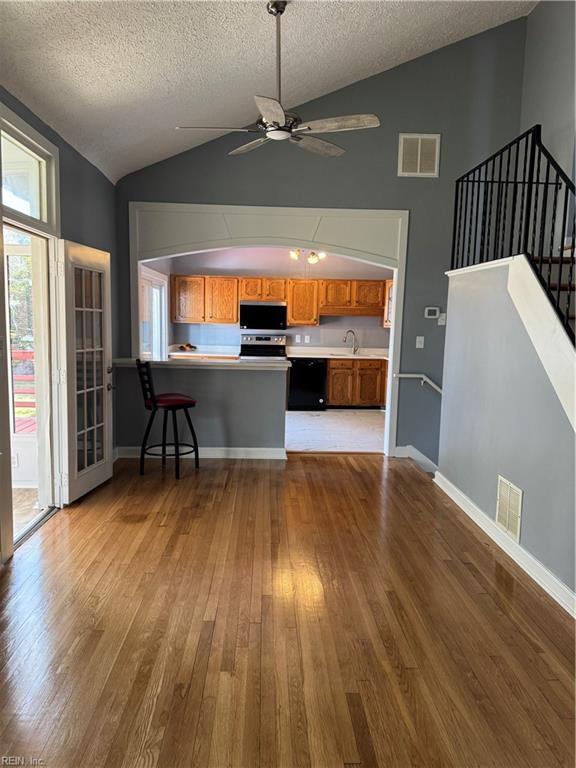 kitchen featuring stainless steel microwave, wood finished floors, visible vents, and brown cabinets