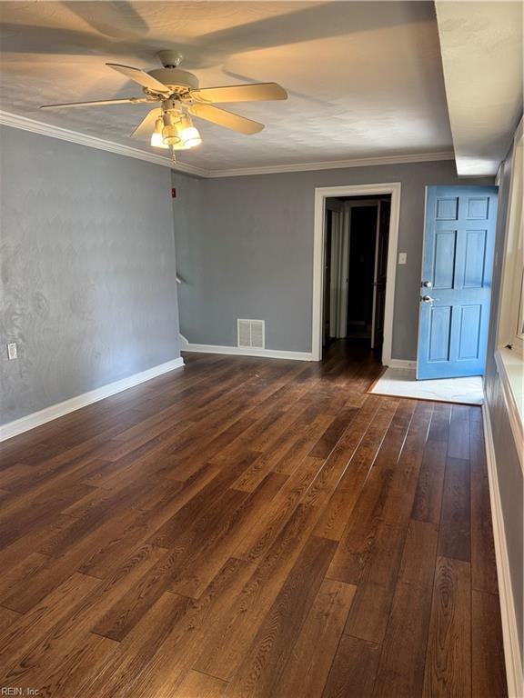 spare room featuring dark wood-style floors, visible vents, and ornamental molding