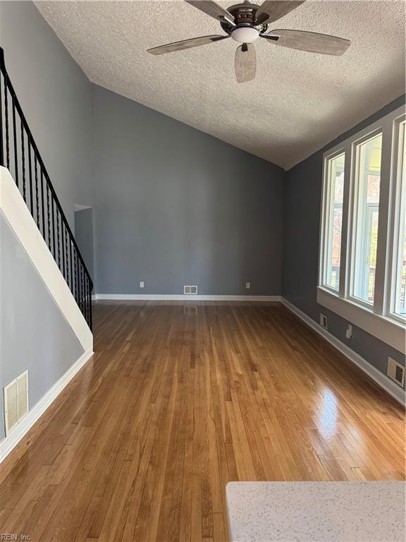 interior space with stairs, hardwood / wood-style floors, visible vents, and baseboards