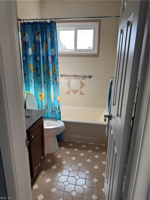 bathroom featuring toilet, tile patterned floors, shower / bathtub combination with curtain, and vanity