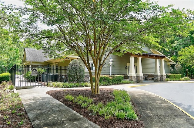 view of front facade with a gate, roof with shingles, and fence