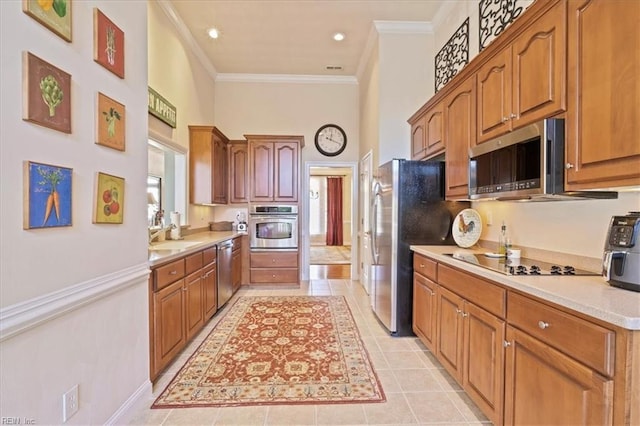 kitchen featuring brown cabinetry, a high ceiling, stainless steel appliances, light countertops, and crown molding