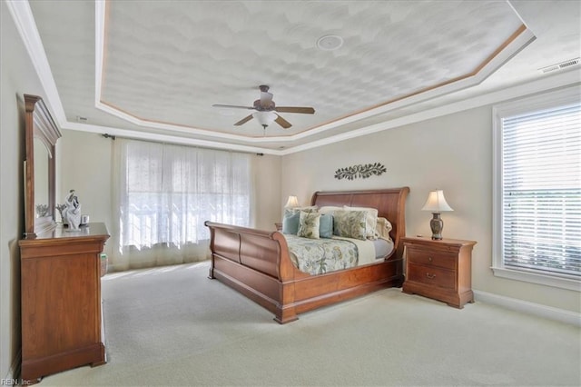 carpeted bedroom with a ceiling fan, visible vents, baseboards, crown molding, and a raised ceiling