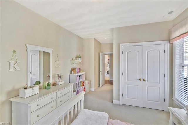 bedroom with a closet, visible vents, light carpet, and baseboards