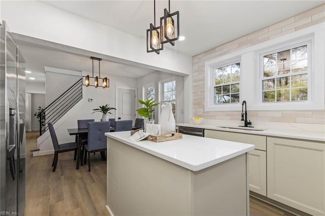 kitchen featuring a center island, a notable chandelier, backsplash, light wood-style floors, and a sink