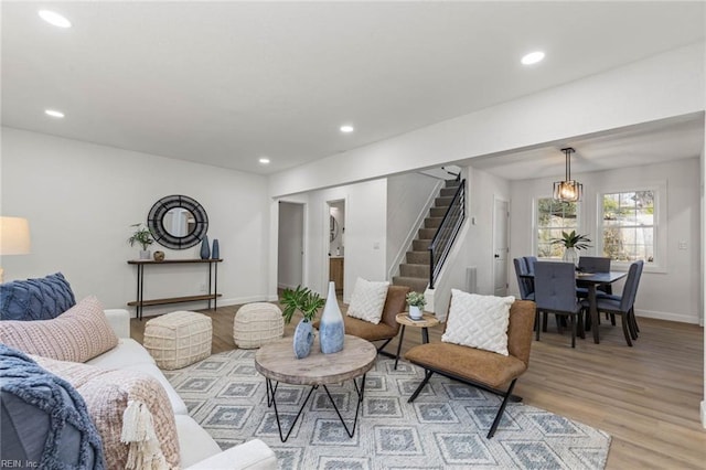 living area with baseboards, stairway, light wood-style flooring, and recessed lighting