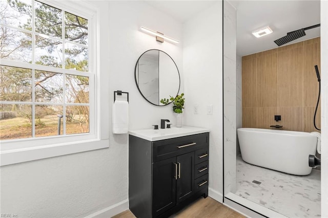 full bathroom featuring a freestanding tub, wood finished floors, vanity, baseboards, and walk in shower