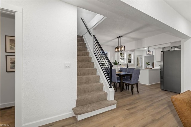 dining space with a notable chandelier, stairs, baseboards, and wood finished floors