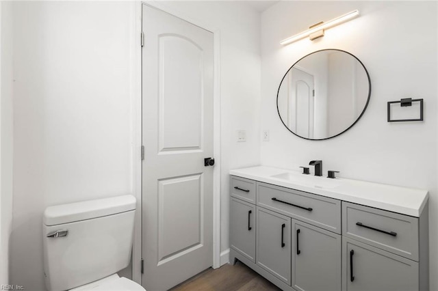 bathroom with toilet, wood finished floors, and vanity