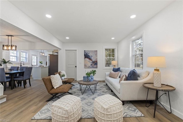 living room with light wood finished floors, baseboards, a notable chandelier, and recessed lighting