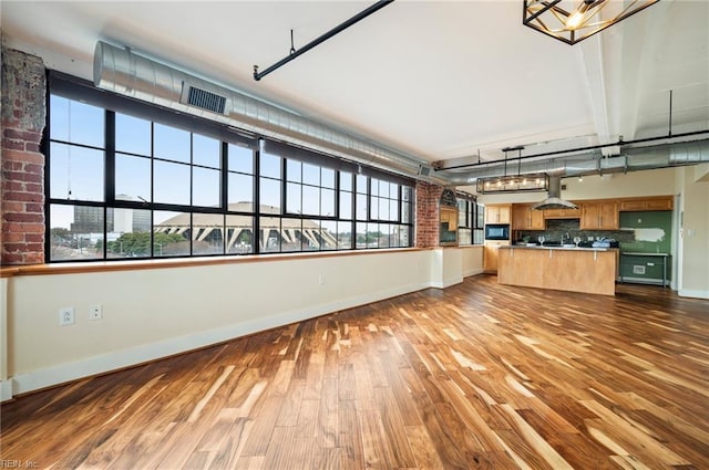 unfurnished living room with a healthy amount of sunlight, baseboards, and wood finished floors