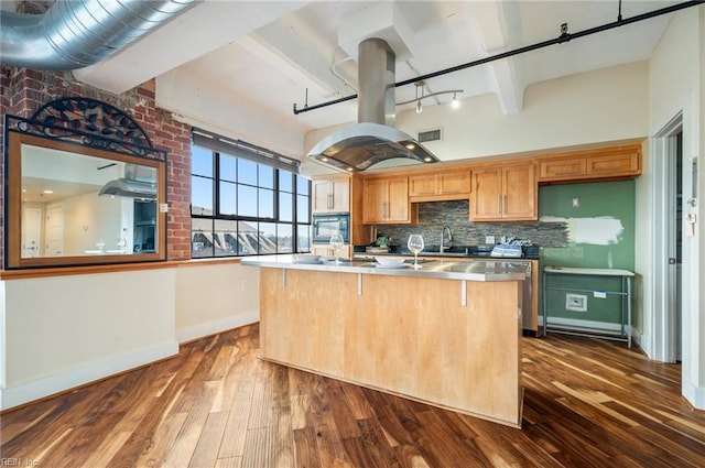 kitchen with tasteful backsplash, dark wood finished floors, island exhaust hood, black microwave, and beam ceiling