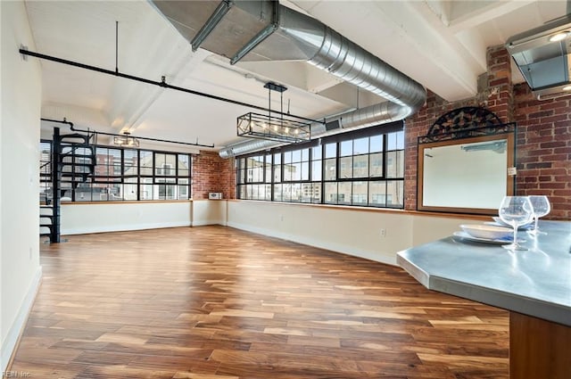 empty room with baseboards, brick wall, and wood finished floors