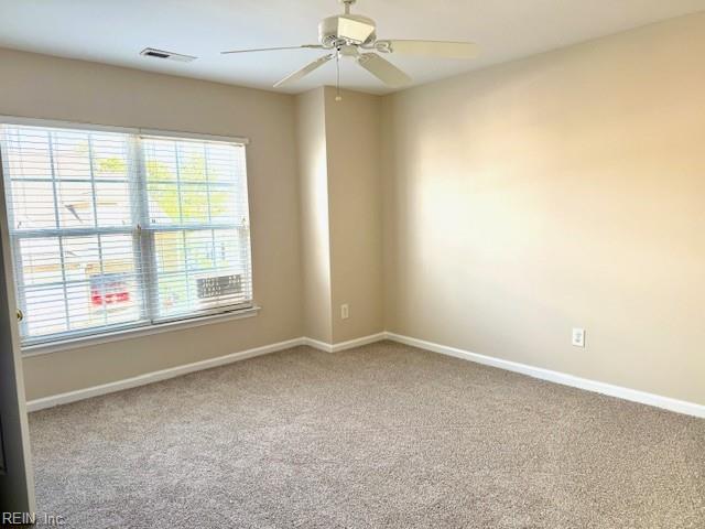 unfurnished room with carpet flooring, visible vents, baseboards, and ceiling fan