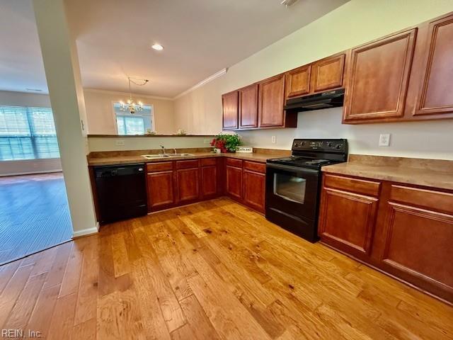 kitchen featuring a sink, black appliances, under cabinet range hood, crown molding, and light wood-type flooring