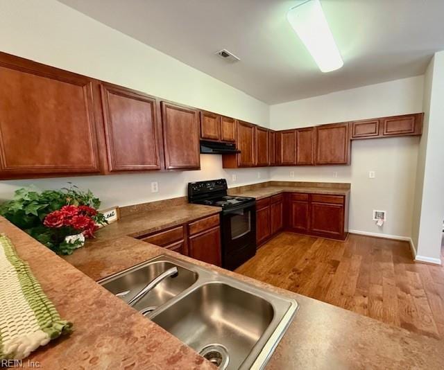 kitchen featuring wood finished floors, visible vents, a sink, black range with electric stovetop, and under cabinet range hood