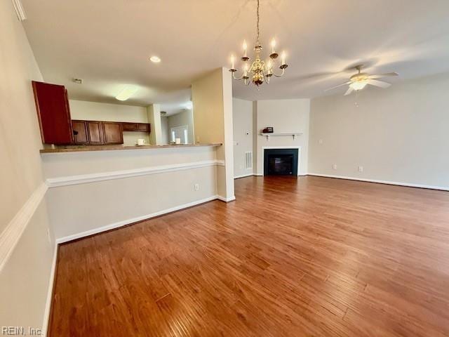 unfurnished living room featuring baseboards, recessed lighting, ceiling fan with notable chandelier, wood finished floors, and a glass covered fireplace