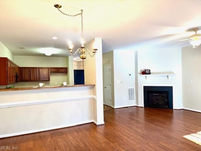 kitchen featuring visible vents, ceiling fan with notable chandelier, wood finished floors, a fireplace, and baseboards