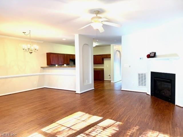 unfurnished living room with dark wood-style floors, visible vents, baseboards, a glass covered fireplace, and ceiling fan with notable chandelier