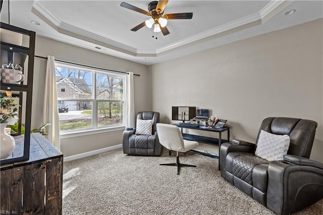 carpeted office with ceiling fan, crown molding, a raised ceiling, and baseboards