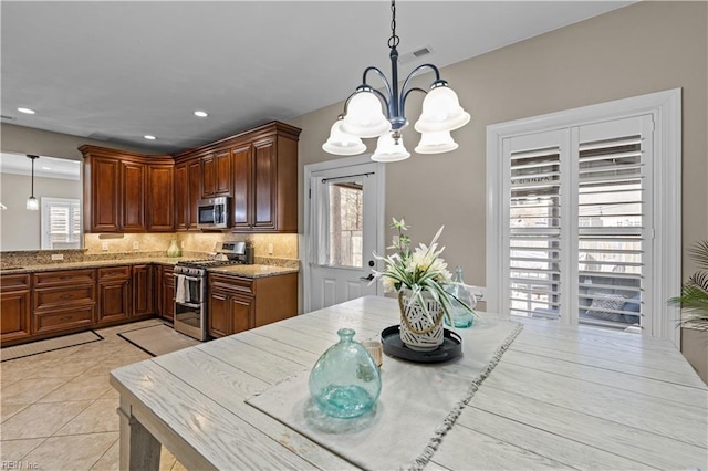 kitchen with light tile patterned floors, hanging light fixtures, backsplash, and appliances with stainless steel finishes