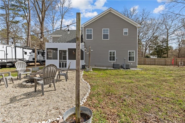 rear view of house with fence, an outdoor fire pit, a lawn, a sunroom, and a patio