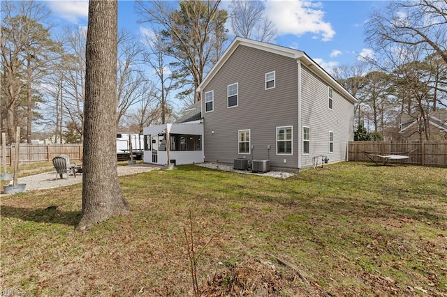 rear view of house featuring a lawn, cooling unit, and a sunroom