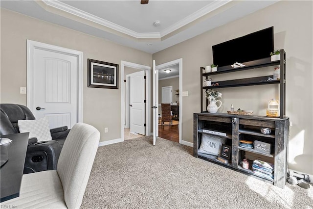 home office with baseboards, a tray ceiling, ornamental molding, carpet flooring, and a ceiling fan