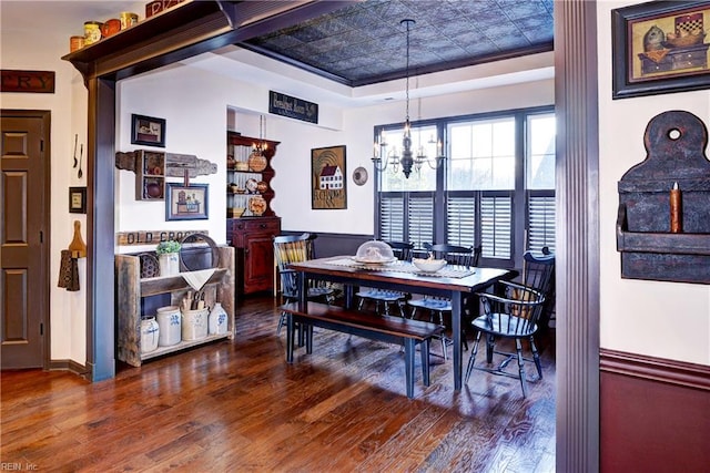 dining space with a chandelier, a tray ceiling, an ornate ceiling, and wood finished floors