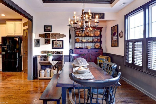 dining room with a wainscoted wall, wood finished floors, visible vents, and an inviting chandelier