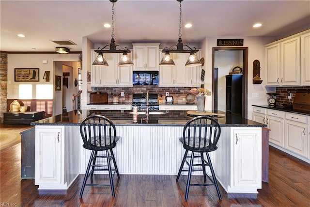 kitchen with a kitchen breakfast bar, visible vents, dark wood finished floors, and black appliances