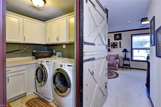 washroom featuring cabinet space, a barn door, visible vents, ornamental molding, and washing machine and clothes dryer