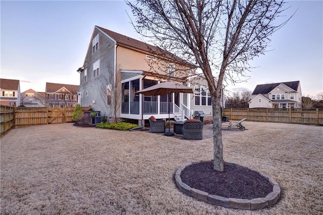 rear view of property featuring a patio, a fenced backyard, and a sunroom