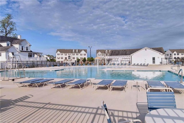 community pool with a residential view, a patio area, and fence