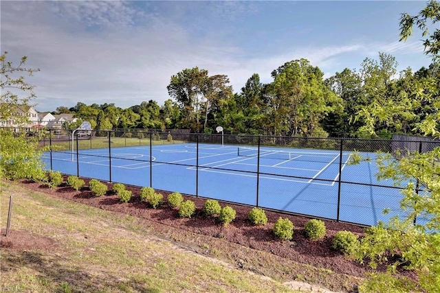 view of tennis court featuring community basketball court and fence