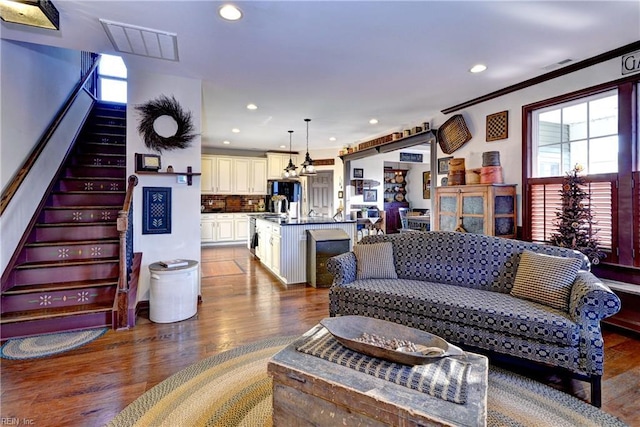 living room with recessed lighting, wood finished floors, visible vents, stairway, and crown molding