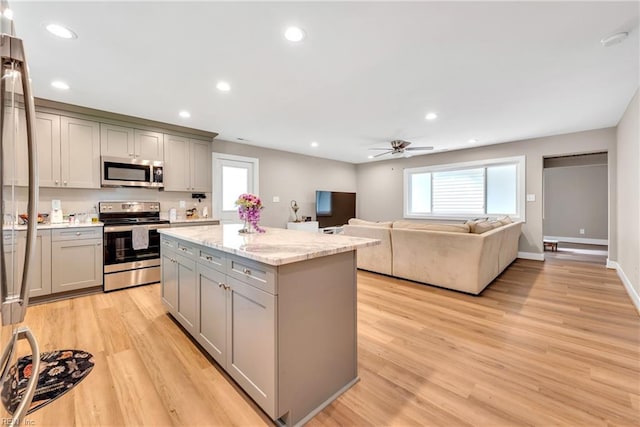 kitchen featuring appliances with stainless steel finishes, light wood-style floors, gray cabinets, and a kitchen island