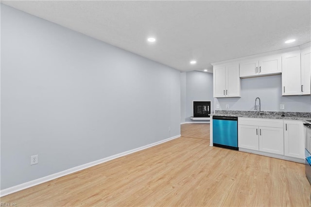 kitchen featuring dishwashing machine, white cabinets, a sink, light wood-type flooring, and baseboards