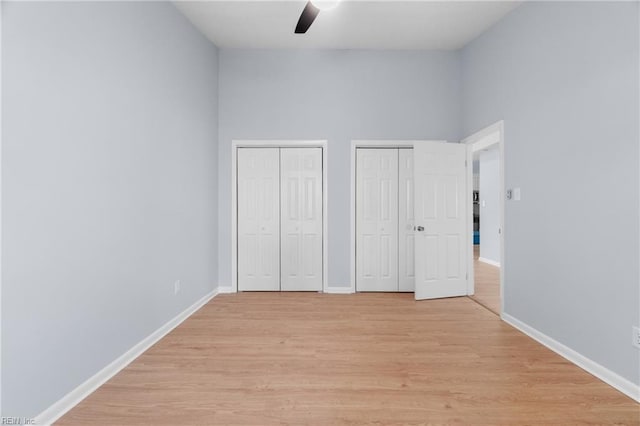 unfurnished bedroom with baseboards, ceiling fan, light wood-type flooring, and multiple closets