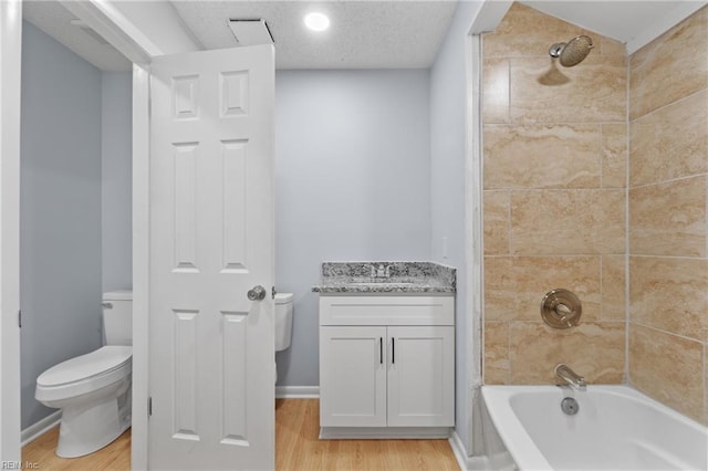 bathroom featuring a textured ceiling, shower / bathtub combination, toilet, wood finished floors, and baseboards